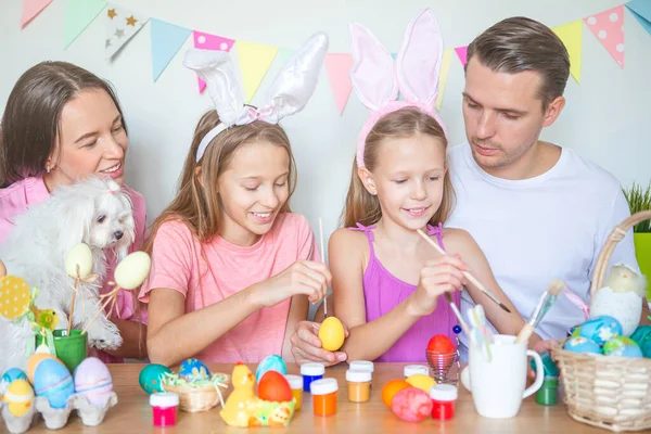 Mutter und ihre kleine Tochter bemalen Eier. Glückliche Familie bereitet sich auf Ostern vor. — Stockfoto