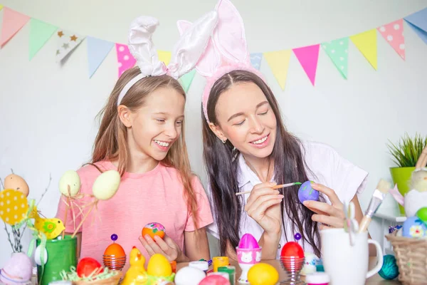 Mutter und ihre kleine Tochter bemalen Eier. Glückliche Familie bereitet sich auf Ostern vor. — Stockfoto