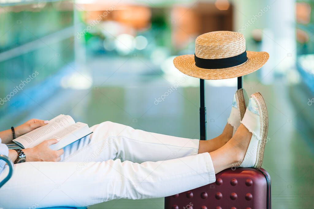 Young woman in an airport lounge waiting for landing. Closeup legs on the baggage