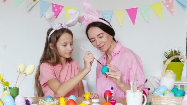 Mother and her little daughter painting eggs. Happy family preparing for Easter. — Stock Video