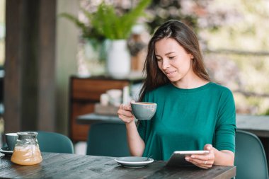 Güzel bir kadın açık kafede kahvaltı yapıyor. Mutlu genç şehir kadını kahve içiyor.