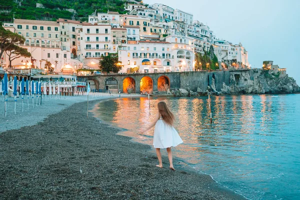 Schattig klein meisje bij zonsondergang in Amalfi stad in Italië — Stockfoto
