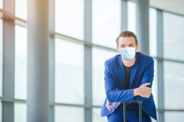 Havaalanındaki salonda uçak bekleyen genç bir adam..