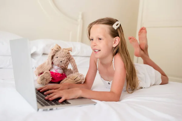 Linda niña haciendo la tarea en el ordenador portátil —  Fotos de Stock