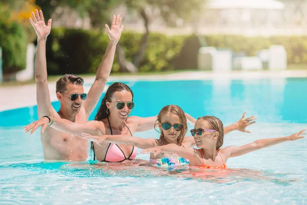 Happy family of four in outdoors swimming pool — Stock Photo, Image