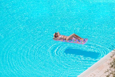 Genç ve güzel bir kadın lüks bir yüzme havuzunda yaz tatilinin tadını çıkarıyor.