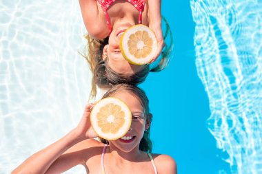 Sevimli küçük kız kardeşler açık havuzda oynuyorlar.