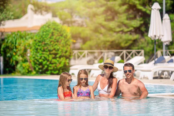 Familia feliz de cuatro en la piscina al aire libre —  Fotos de Stock