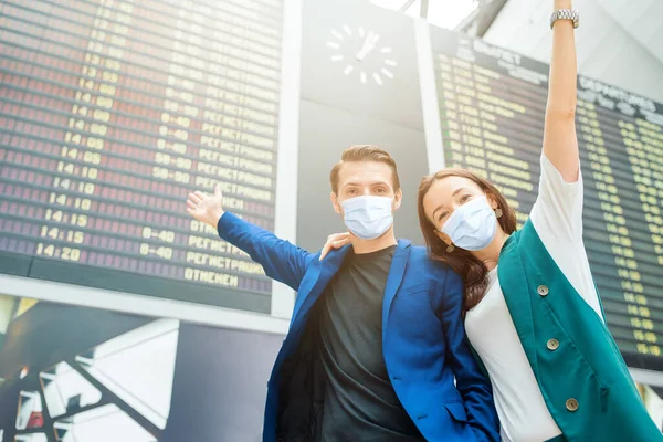 Junges Paar auf internationalem Flughafen blickt auf die Fluginformationstafel — Stockfoto