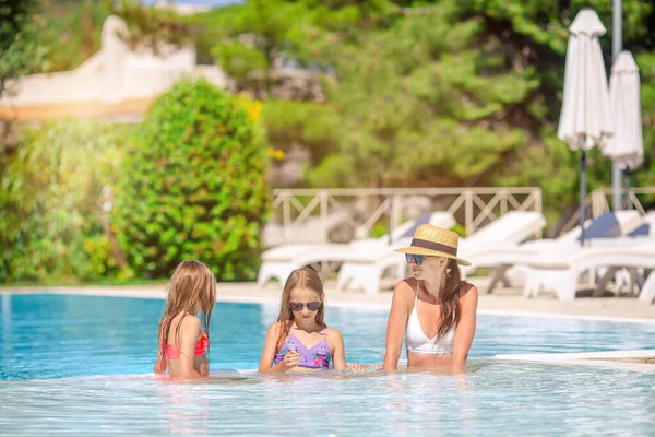 Mãe e duas crianças desfrutando de férias de verão na piscina de luxo — Fotografia de Stock