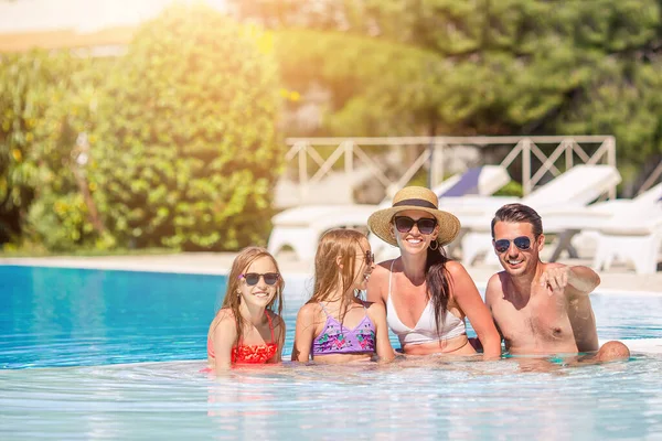 Familia feliz de cuatro en la piscina al aire libre —  Fotos de Stock