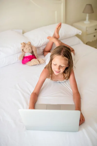 Söt liten flicka gör läxor på laptop — Stockfoto