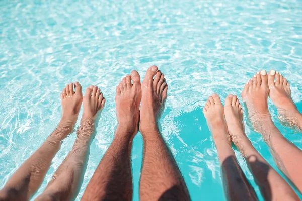 Primo piano di quattro persone gambe a bordo piscina — Foto Stock