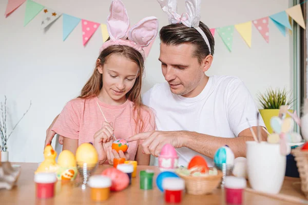 Vater und seine kleine Tochter bemalen Eier. Glückliche Familie bereitet sich auf Ostern vor. — Stockfoto