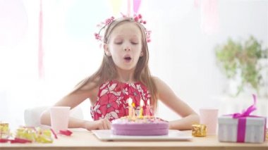 Beyaz kız rüyasında gülümsüyor ve gökkuşağı pastasına bakıyor. Balonlarla dolu renkli bir arka plan. Doğum günü partisi ve dilek konsepti.