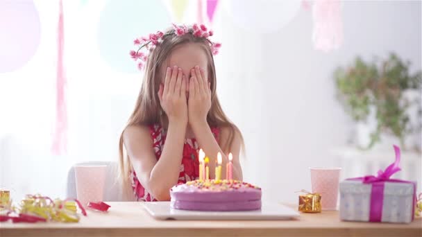 Kaukasiska flicka är drömskt ler och tittar på födelsedag regnbåge tårta. Festlig färgglad bakgrund med ballonger. Födelsedagsfest och önskemål koncept. — Stockvideo