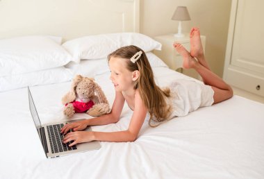 Ciddi liseli kız dizüstü bilgisayar ve ders kitabı ile masada oturuyor ve ödev yapıyor..