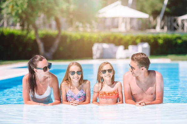 Familia feliz de cuatro en la piscina al aire libre — Foto de Stock