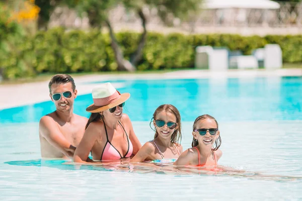 Happy family of four in outdoors swimming pool — Stock Photo, Image