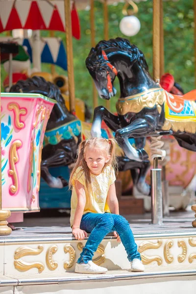 一个可爱的小女孩站在外面的旋转木马旁边 — 图库照片
