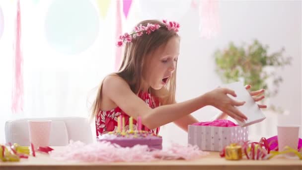 Blank meisje lacht dromerig en kijkt naar verjaardagsregenboogtaart. Feestelijke kleurrijke achtergrond met ballonnen. Verjaardagsfeest en wensenconcept. — Stockvideo