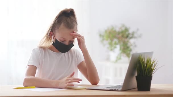 Serieuze schoolmeisje zitten aan tafel met laptop en leerboek en het doen van huiswerk. — Stockvideo