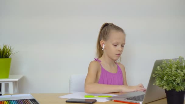 Σοβαρή μαθήτρια κάθεται στο τραπέζι με το laptop και το βιβλίο και να κάνει την εργασία. — Αρχείο Βίντεο