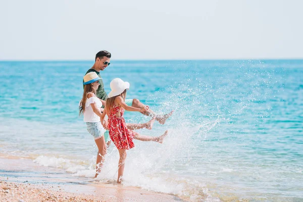 Bambini adorabili e il loro papà in spiaggia durante le vacanze estive — Foto Stock