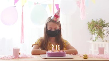 Beyaz kız rüyasında gülümsüyor ve gökkuşağı pastasına bakıyor. Balonlarla dolu renkli bir arka plan. Doğum günü partisi ve dilek konsepti.