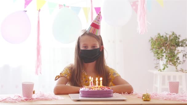 Caucasian girl is dreamily smiling and looking at birthday rainbow cake. Festive colorful background with balloons. Birthday party and wishes concept. — Stock Video