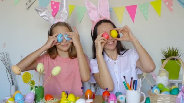 Madre y su pequeña hija pintando huevos. Familia feliz preparándose para la Pascua. — Vídeo de stock