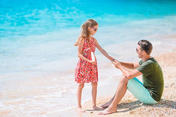 어린 아빠 가 해변에서 딸 코에 햇볕 크림을 바르고 있어. 태양 보호 — 스톡 사진