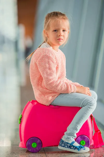 Liebenswertes kleines Mädchen im Flughafen mit ihrem Gepäck, das auf das Boarding wartet — Stockfoto