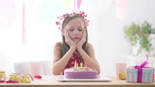 白人の少女は誕生日にマスクをしている。風船で祭りのカラフルな背景。誕生会と願いのコンセプト. — ストック動画