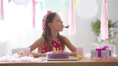 Beyaz kız rüyasında gülümsüyor ve gökkuşağı pastasına bakıyor. Balonlarla dolu renkli bir arka plan. Doğum günü partisi ve dilek konsepti.