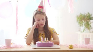 Beyaz bir kız doğum gününde hayal kırıklığına uğrattı. Balonlarla dolu renkli bir arka plan. Doğum günü partisi ve dilek konsepti.