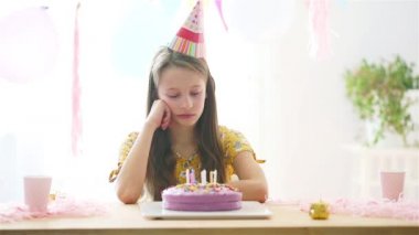 Beyaz bir kız doğum gününde hayal kırıklığına uğrattı. Balonlarla dolu renkli bir arka plan. Doğum günü partisi ve dilek konsepti.