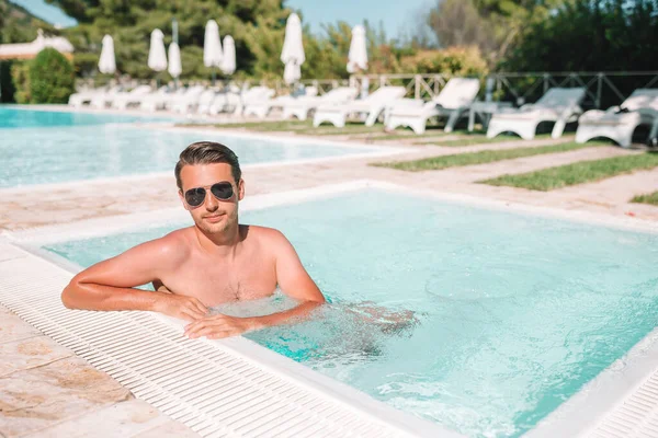 Young man with laptop in outdoor swimming pool. — Stock Photo, Image