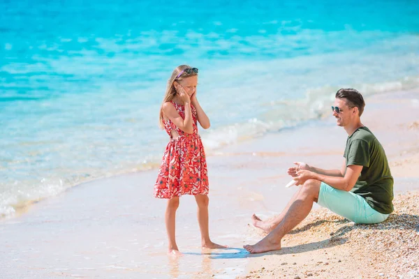 Νεαρός πατέρας βάζει αντηλιακό στη μύτη της κόρης του στην παραλία. Προστασία από τον ήλιο — Φωτογραφία Αρχείου