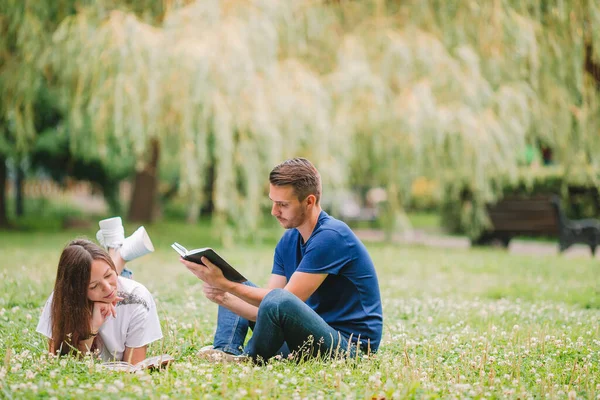 Junges romantisches Paar liegt im Park und liest Bücher — Stockfoto