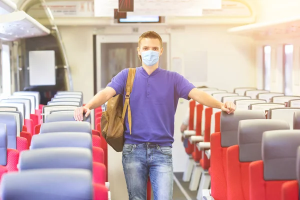 Młody człowiek podróżuje pociągiem i nosi maskę. — Zdjęcie stockowe