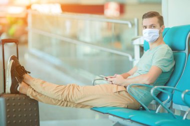 Havaalanındaki salonda uçak bekleyen genç bir adam..