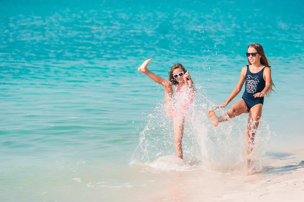 Kleine fröhliche lustige Mädchen haben viel Spaß am tropischen Strand beim gemeinsamen Spielen. — Stockfoto