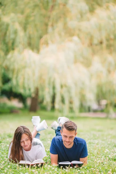 Junges romantisches Paar liegt im Park und liest Bücher — Stockfoto
