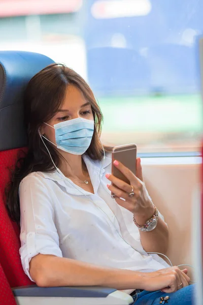 Młoda kobieta podróżuje pociągiem i nosi maskę — Zdjęcie stockowe