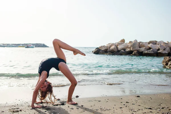 Ενεργό κοριτσάκι στην παραλία διασκεδάζει πολύ. Χαριτωμένο παιδί κάνει σπορ ασκήσεις στην παραλία — Φωτογραφία Αρχείου