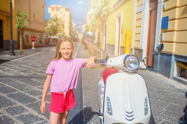 Schattig klein meisje glimlachend op de brommer buiten — Stockfoto