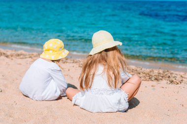 Küçük mutlu komik kızlar tropikal plajda birlikte oynarken çok eğlenirler..