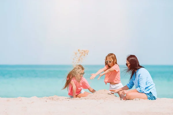 在热带海滩建造沙堡的母亲和小女儿 — 图库照片