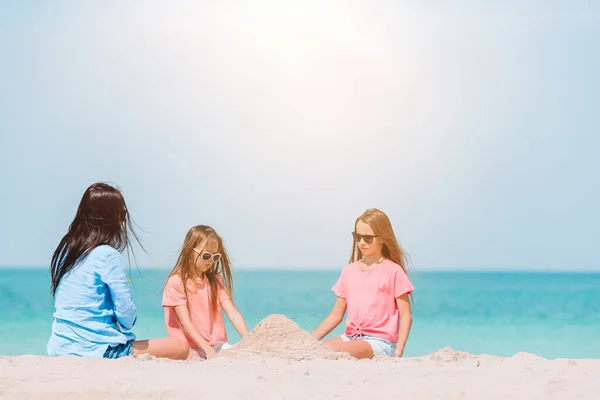 Matka i małe córeczki robiące zamek z piasku na tropikalnej plaży — Zdjęcie stockowe